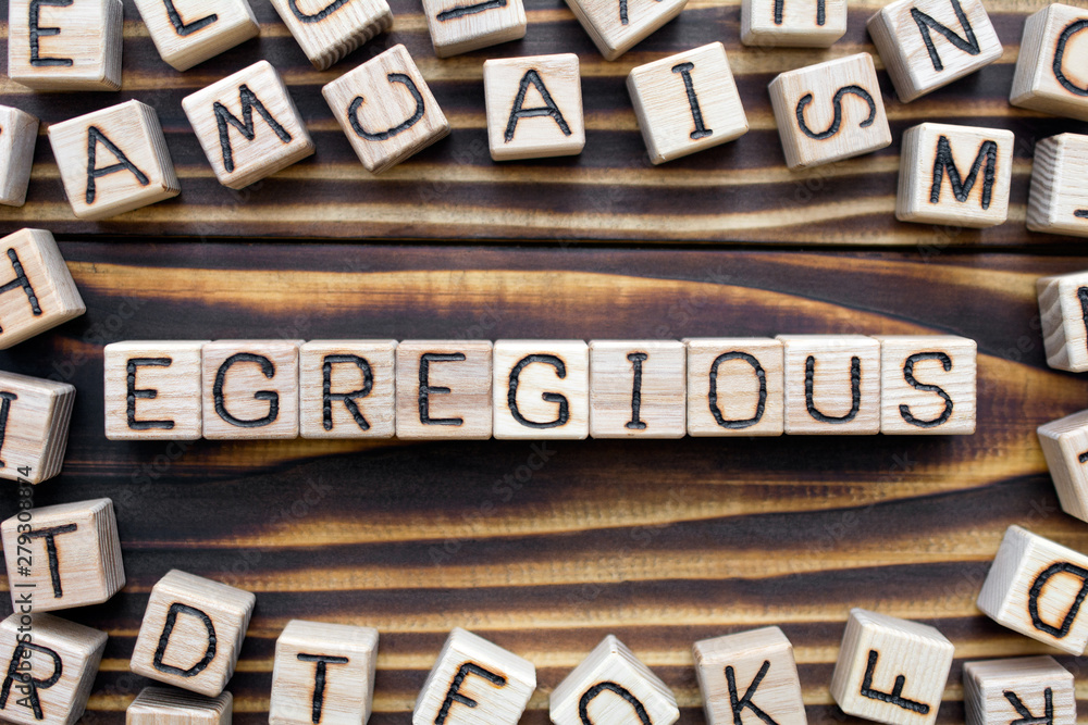 egregious wooden cubes with letters, extremely bad beyond any reasonable degree concept, around the cubes random letters, top view on wooden background egregious wooden cubes with letters, extremely bad beyond any reasonable degree concept, around the cubes random letters, top view on wooden background