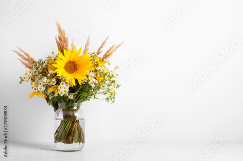 Field flowers in a glass vase. Summer bouquet of flowers on the white background