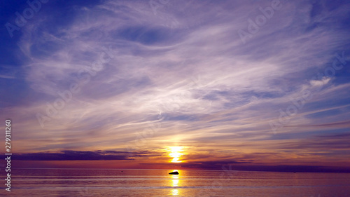 Beautiful multicolored sunset over sea. stone lies on a sunny path reflecting the sunset in the sea