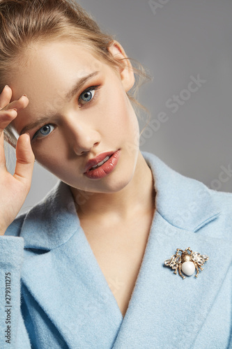 Tableau sur toile Portrait of lady with tied back fair hair, wearing sky blue coat with brooch in view of bee with transparent crystals on wings