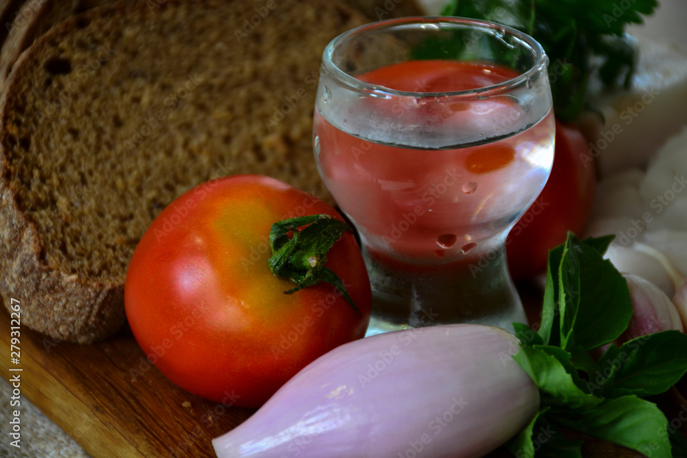 Freshly baked bread on a wooden cutting board with bacon, tomatoes, onions, garlic, basil and a shot of vodka Freshly baked bread on a wooden cutting board with bacon, tomatoes, onions, garlic, basil and a shot of vodka