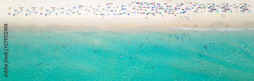 Aerial view crowded public beach with colourful umbrellas, Aerial view of sandy beach with tourists swimming in beautiful clear sea water. © Kalyakan
