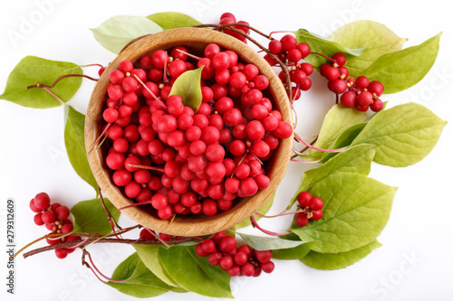 Schisandra chinensis or five-flavor berry. Fresh red ripe berries with leaves in wooden bowl on white background. Top view. photo