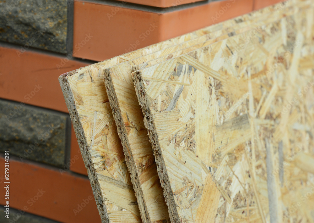 Oriented strand board (OSB) near brick house wall Oriented strand board (OSB) near brick house wall