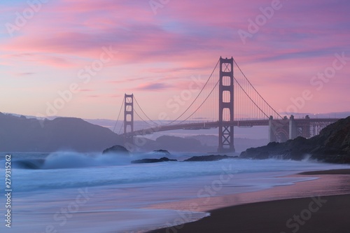 Classic panoramic view of famous Golden Gate Bridge seen from scenic Baker Beach in beautiful golden evening light on a dusk with blue sky and clouds in summer, San Francisco, California, USA