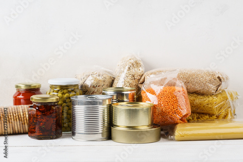 Obraz na plátně Various canned food and raw cereal grains on a table.