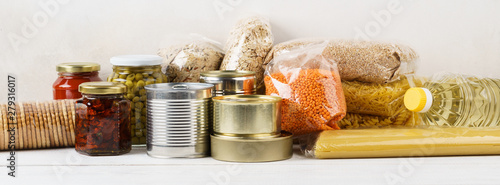 Obraz na plátně Various canned food and raw cereal grains on a table.