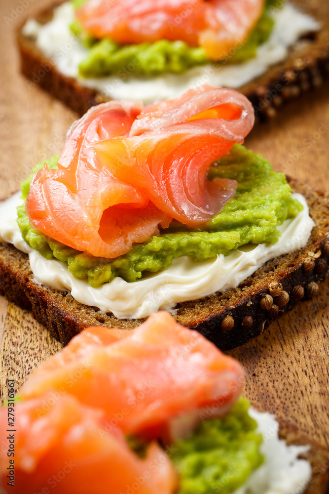 open sandwich with avocado and salmon on wood board