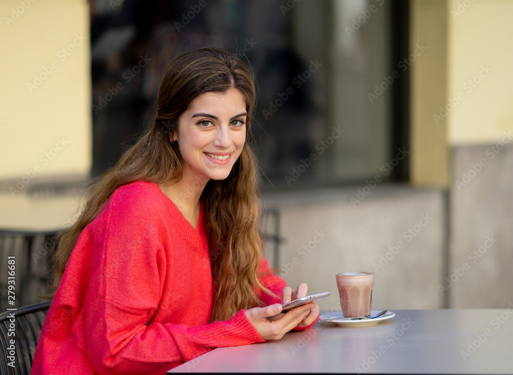 Attractive young woman using smart mobile phone app in a coffee shop terrace Attractive young woman using smart mobile phone app in a coffee shop terrace