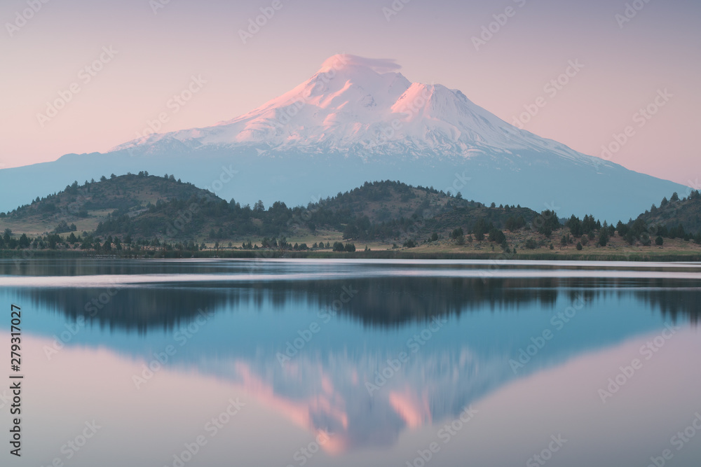 A reflection of snow capped Mount Shasta in a clear water in lake at sunrise in California State, USA. Mount Shasta is a volcano at the southern end of the Cascade Range in Siskiyou County A reflection of snow capped Mount Shasta in a clear water in lake at sunrise in California State, USA. Mount Shasta is a volcano at the southern end of the Cascade Range in Siskiyou County