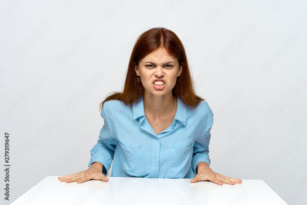 portrait of young angry woman sitting at table portrait of young angry woman sitting at table