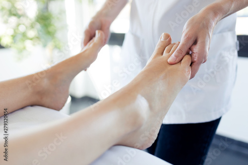 Pregnant woman enjoying reflexology foot massage in wellness spa.