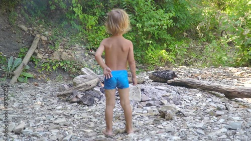 little boy by the fire in the forest. summer, adventure, childhood. concept - vacation. photo