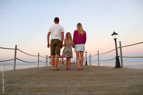 Glückliche Familie schlendert über einem Steg am Meer