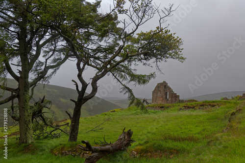 An old Abandoned Scottish Cottage ruin high up a Valley on the Old Military Road to Banchory, on a wet, cold Summers day in June. Aberdeenshire. photo