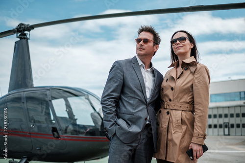 Young business couple near private helicopter
