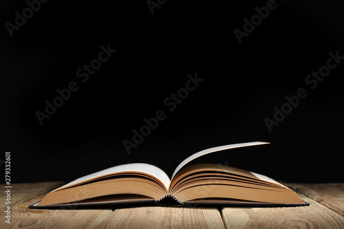 open book on a wooden table and black background  with copy space for your text