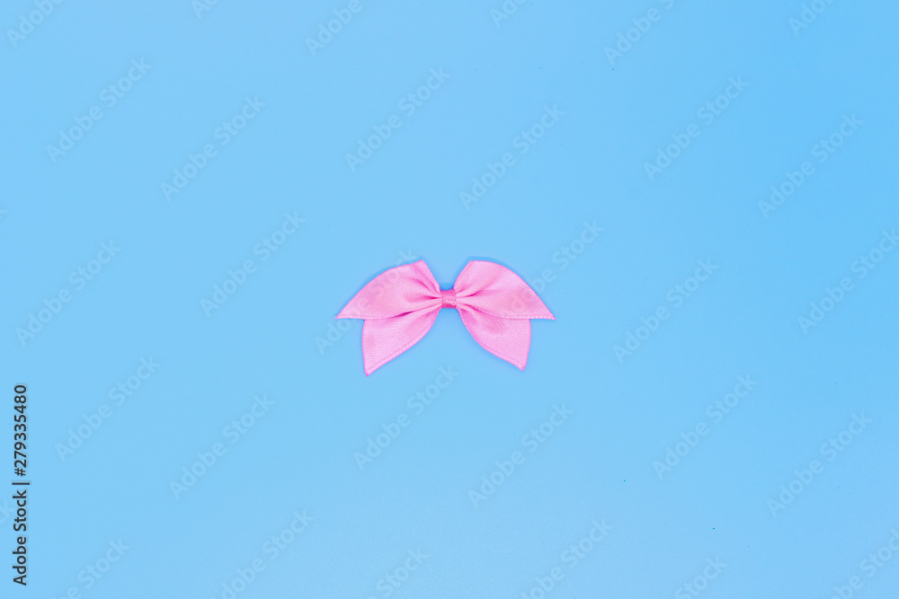 Realistic pink ribbon, bow on a blue background, the concept of a holiday card