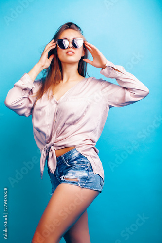 young pretty girl in sunglasses posing happy smiling on blue background, lifestyle people on summer vacation concept