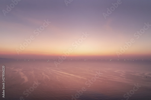 Dramatic atmosphere panorama aerial view of beautiful twilight sky with cloud and sea texture wave show small light bokeh of fishing boats background for silhouette object.