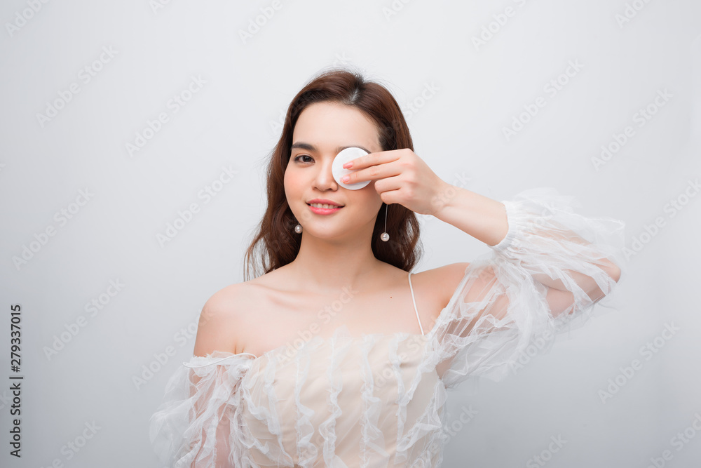 Beauty portrait of a cheerful young topless woman removing face make-up with a cotton pad isolated over white background Beauty portrait of a cheerful young topless woman removing face make-up with a cotton pad isolated over white background