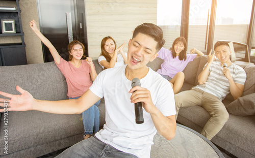 Group of friends playing karaoke at home