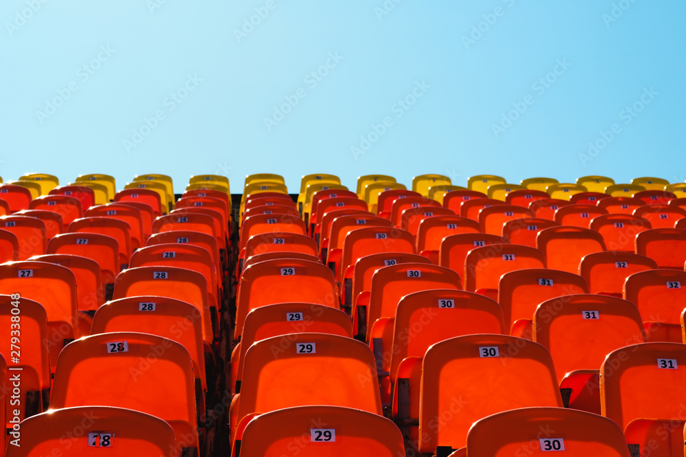 Fototapeta premium red plastic seats against a bright blue sky