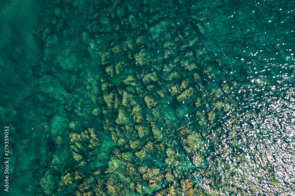 Fototapeta premium Aerial view of rocky seaside. Rocky stones in the ocean. Aerial photography of beautiful rocky seashore.