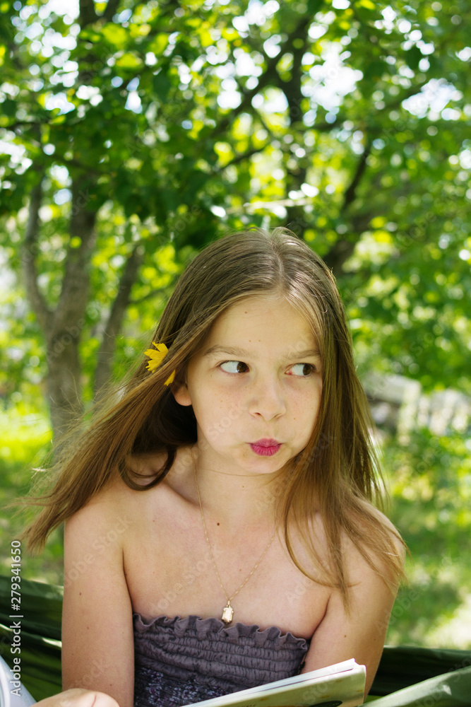 Beautiful girl reading a book and lying on a hammock in the garden Beautiful girl reading a book and lying on a hammock in the garden