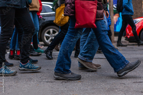 Environmental activists march in city. Many legs are viewed marching in a town center as environmentalists demonstrate together, bustling street scene during a community protest.