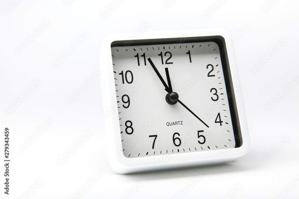 white square analog alarm clock on white background. five minutes to twelve white square analog alarm clock on white background. five minutes to twelve