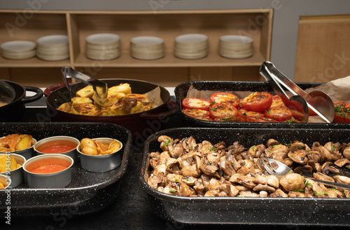 Selection of self service catering continental breakfast buffet display, catering brunch table food buffet filled with delicious food, grill, bacon, eggs, hot station in a hotel or restaurant setting