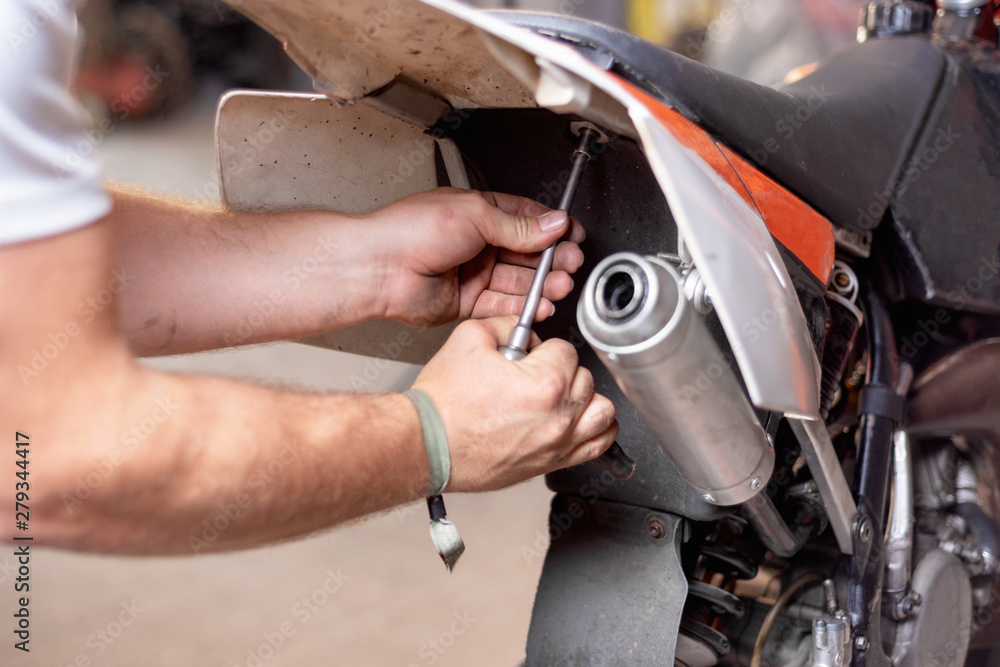 Fototapeta premium Motorbike mechanic repairing an exhaust pipe system at garage .