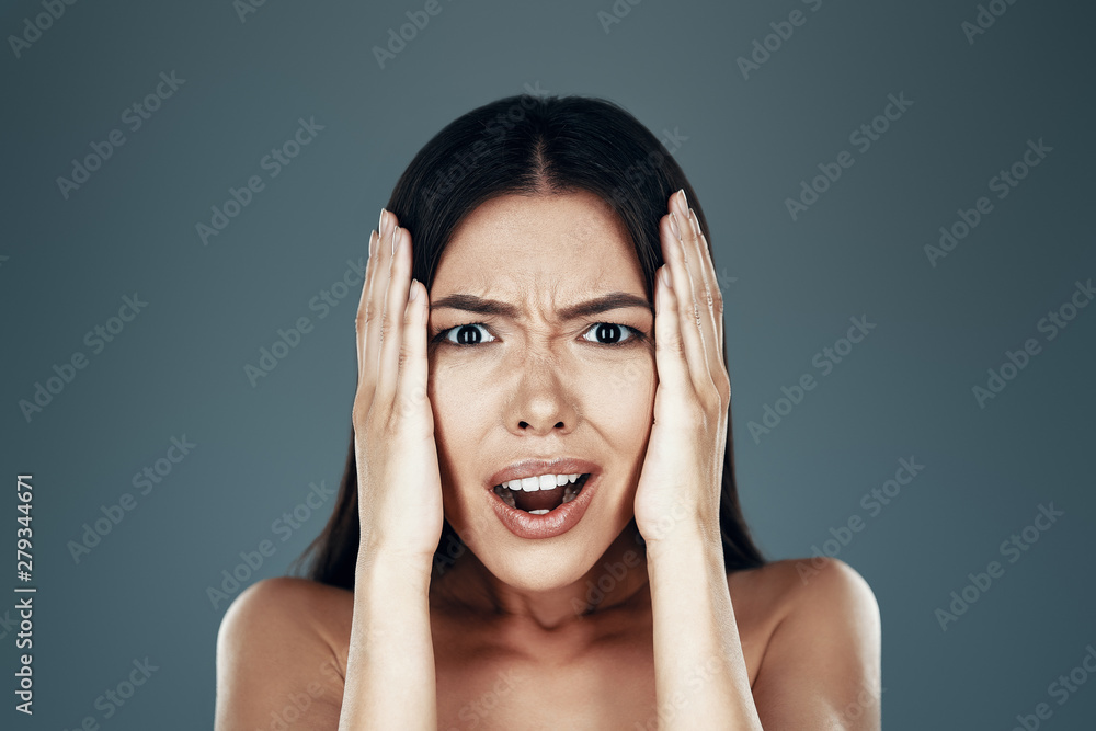 What? Surprised young Asian woman looking at camera and making a face while standing against grey background What? Surprised young Asian woman looking at camera and making a face while standing against grey background