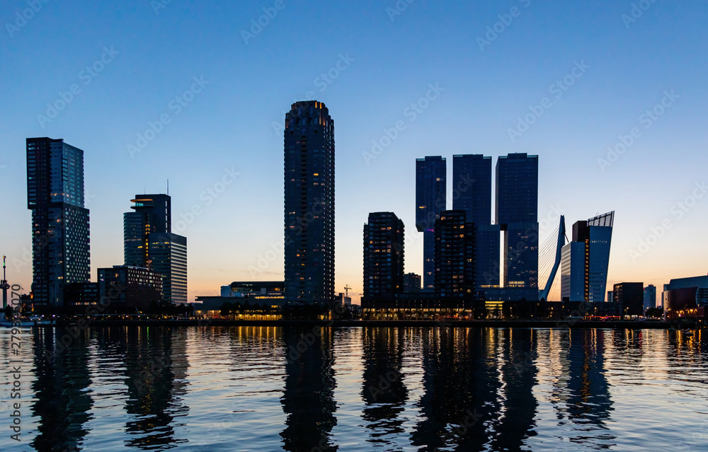 Rotterdam city Netherlands illuminated skyscrapers, reflections on the water, sunset time, blue clear sky