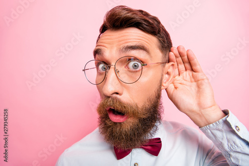 Close up portrait of funny funky loony geek astonished hipster holding palm near ear isolated pastel background