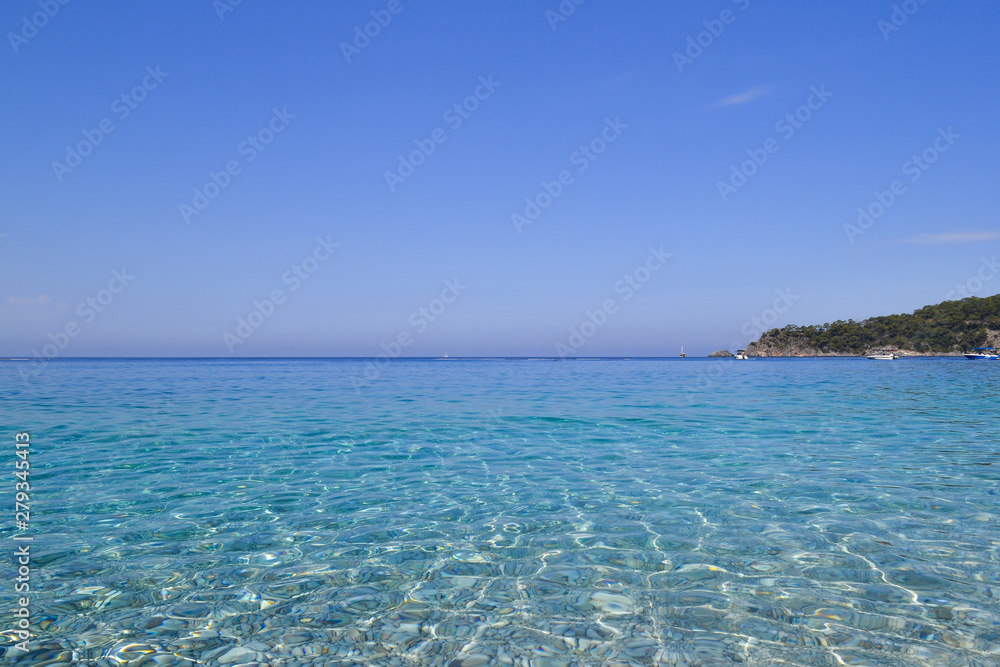 Sea view. Transparent water and calm turquoise sea with sun highlights