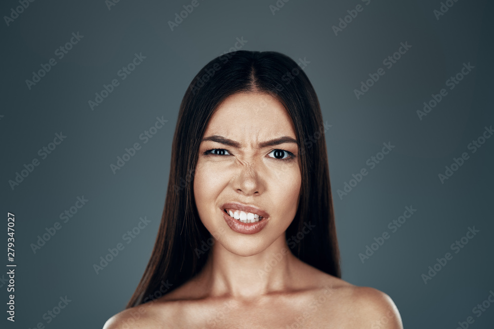 What? Confused young Asian woman making a face and looking at camera while standing against grey background What? Confused young Asian woman making a face and looking at camera while standing against grey background