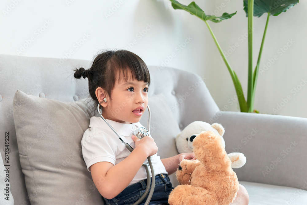 Little asian girl play with baby doll toy.Little asian girl hold stethoscope in hand and check baby doll toy. Little asian girl play with baby doll toy.Little asian girl hold stethoscope in hand and check baby doll toy.