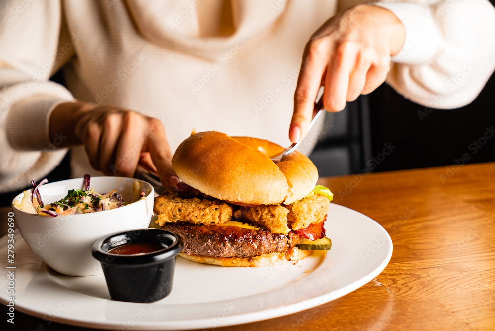 .Young woman eating burger in restaurant .Young woman eating burger in restaurant