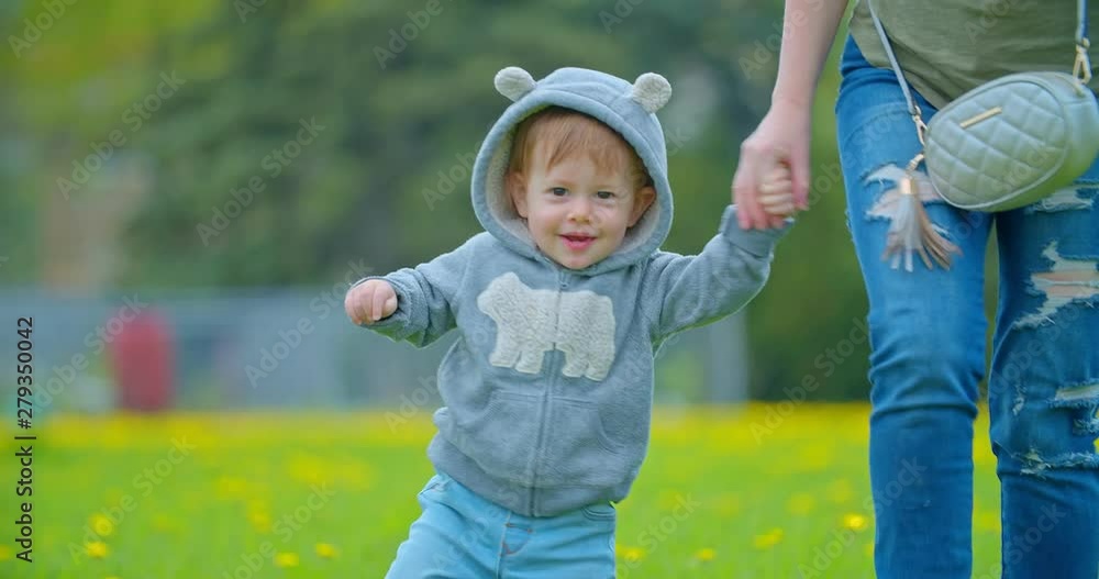 Little boy learns to walk. Mother is teaching her child to do the first steps Little boy learns to walk. Mother is teaching her child to do the first steps