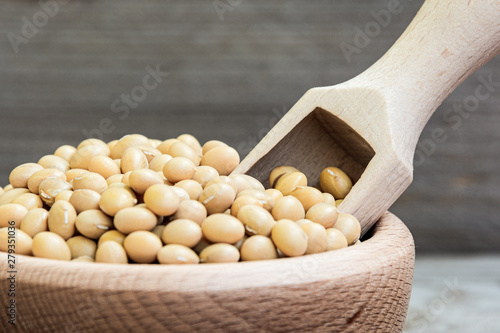 Tableau sur toile Dried raw soya in wooden bowl and measuring cup on wooden background