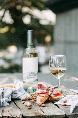 Bruschettes and a picnic with prosciutto. White wine with a glass in nature in Italy.