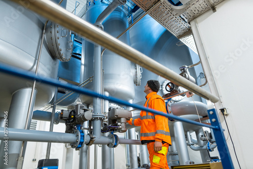 Man at work in a water utility inspecting pipes leading to the pump