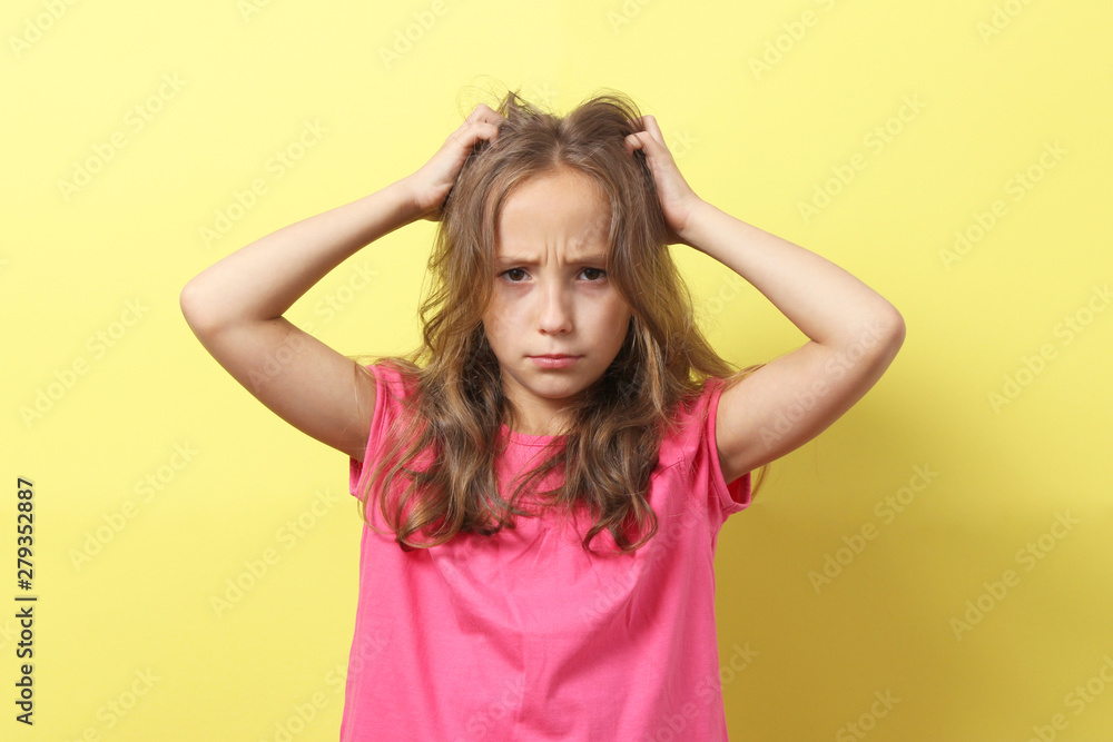 Fototapeta premium The girl is scratching her head on a colored background.