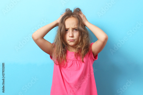 The girl is scratching her head on a colored background.  photo