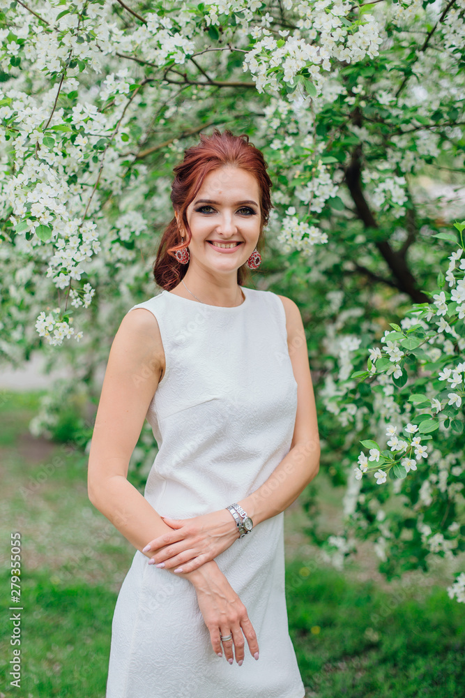 Charming woman wearing beautiful white dress under the apple tree Charming woman wearing beautiful white dress under the apple tree