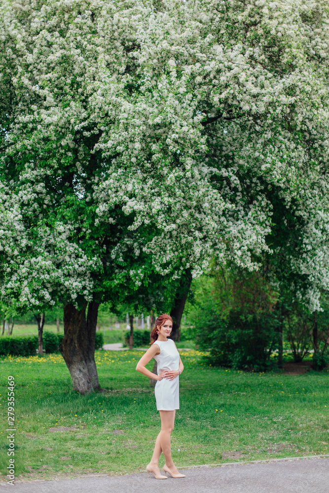 Charming woman wearing beautiful white dress under the apple tree Charming woman wearing beautiful white dress under the apple tree