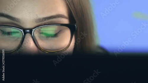 Happy young woman with glasses eyes looking at the monitor and surprised surprised by the good news, surfing the Internet, extreme close-up with reflection