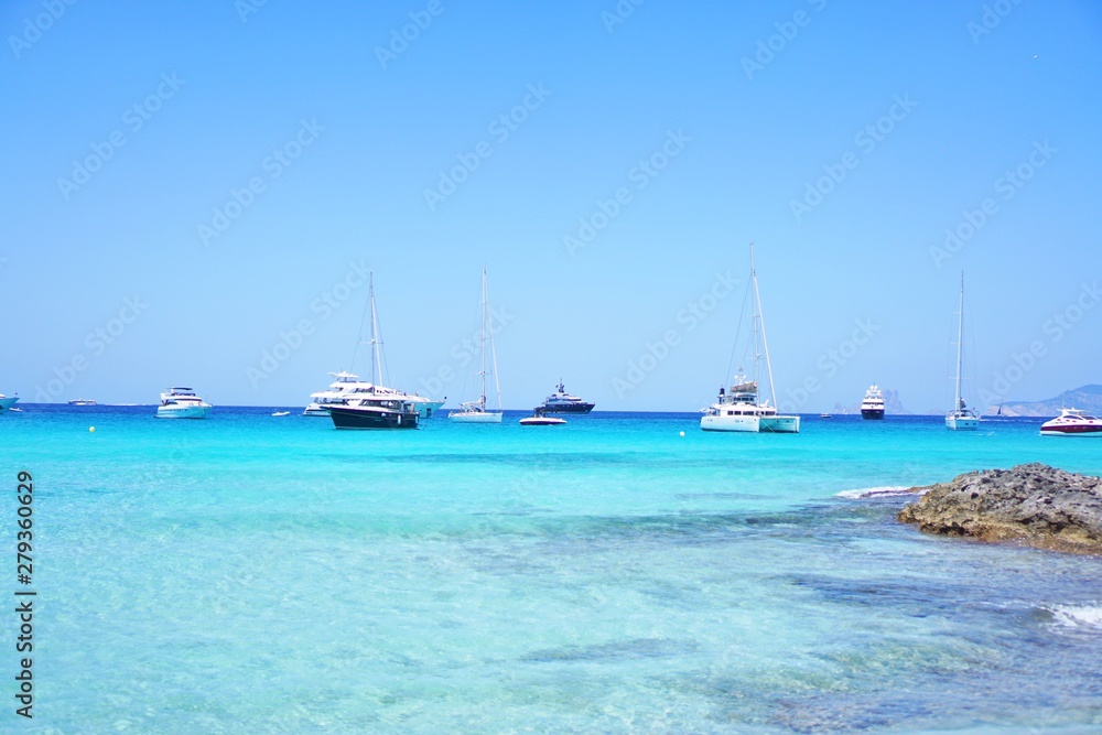 Yachten und Katamaran im karibischen Meer am Horizont im klaren türkisen Wasser